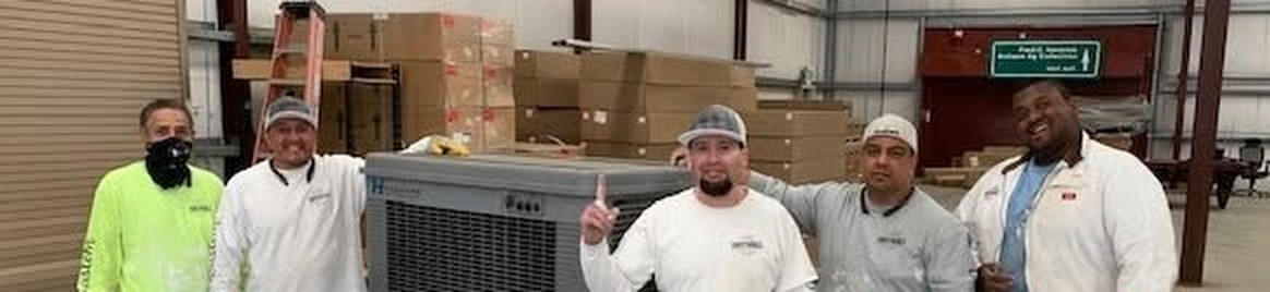 Five men in work clothes standing around an evaporative cooler in a warehouse