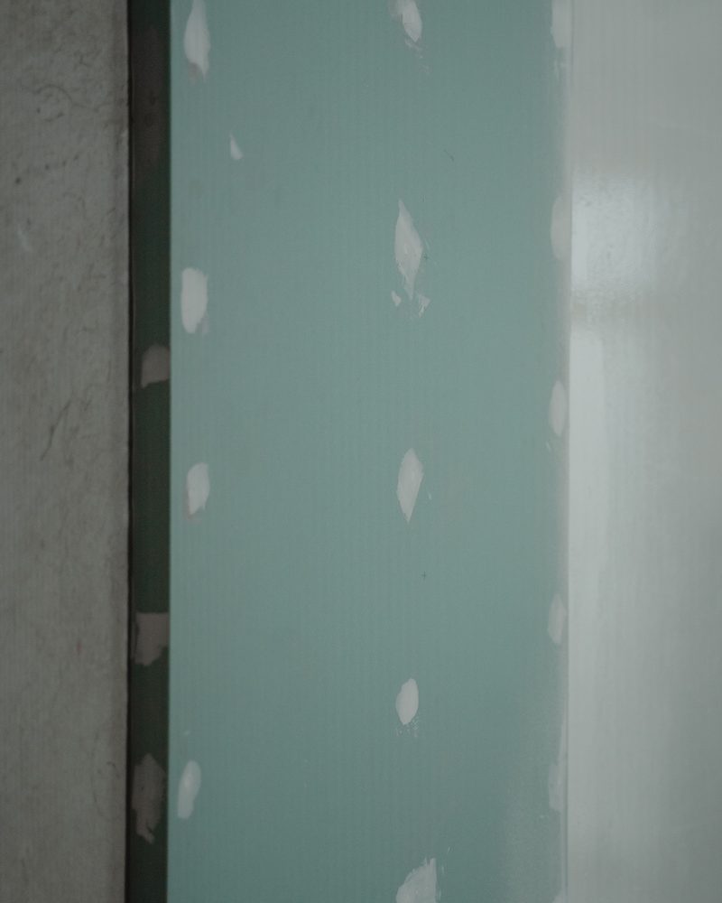 Green drywall boards on a wall with screw heads filled in