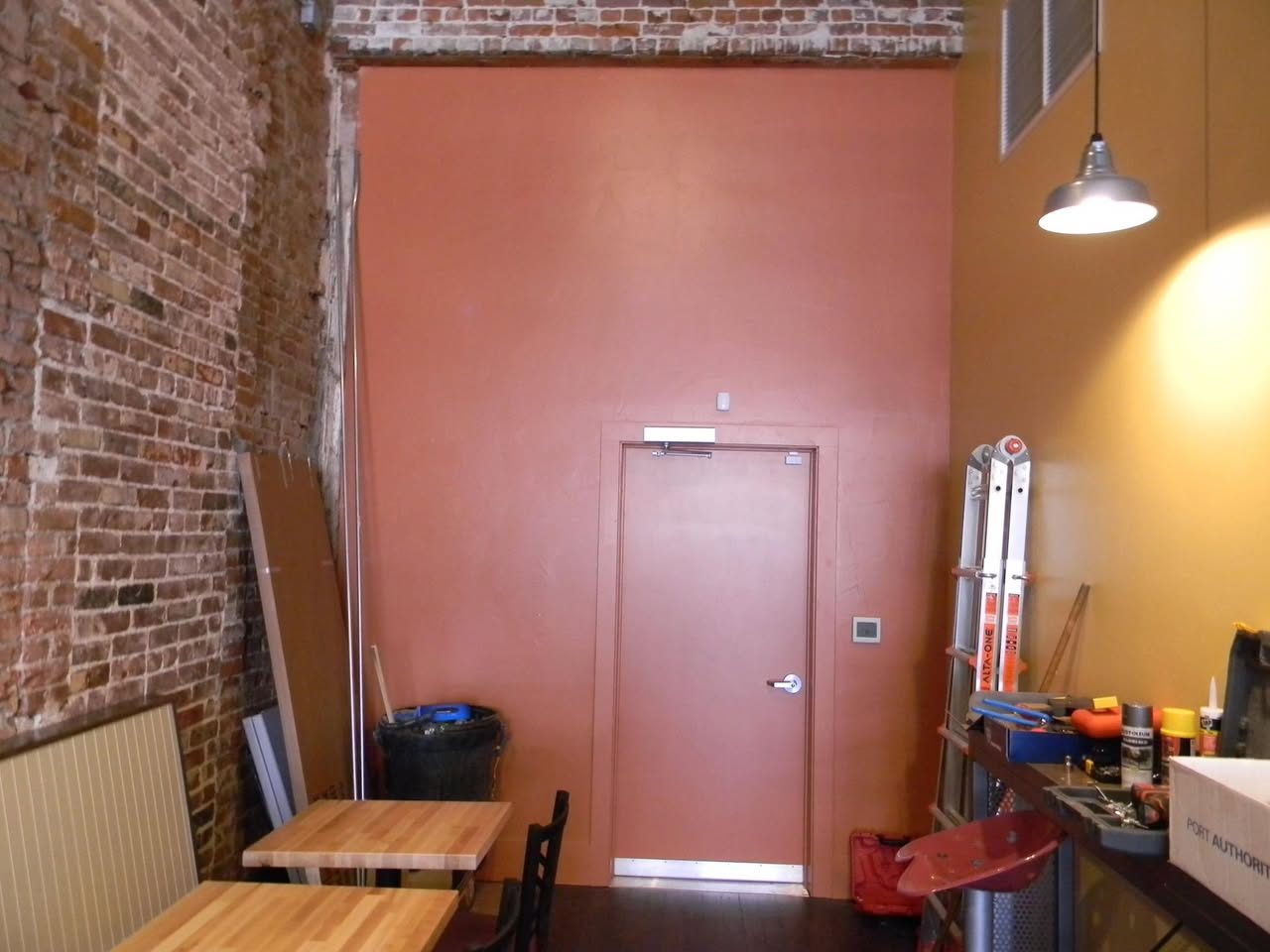 Painted interior wall with a doorway, beside an exposed brick wall